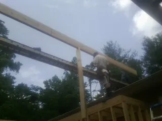 Carpenter setting a ridge beam over a new addition frame — Ice Dam Removal by Roofing Brothers in Lugoff