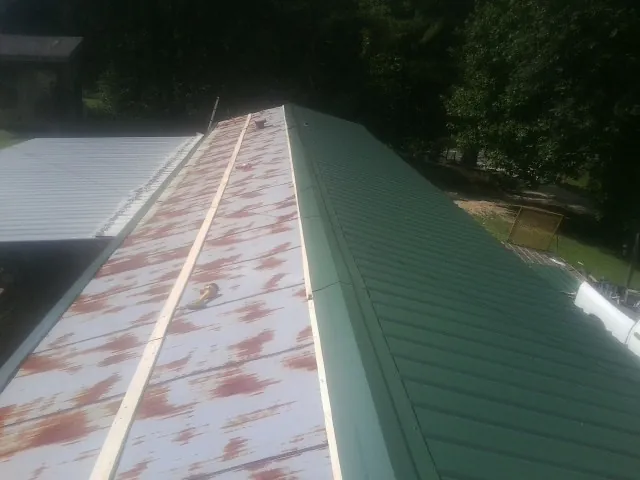 Old rusted panels beside newly installed green metal roofing — Wind Damage Roof Repair by Roofing Brothers in Lugoff