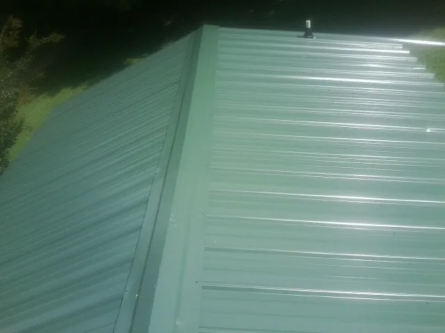 New green metal panels meeting at the ridge of a roof — Flat Roof Repair work by our crew in Lugoff
