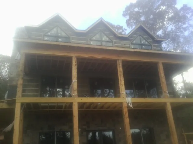 Dormers and porch framing on a large log home under construction — Roof Coating work by our crew in Lugoff
