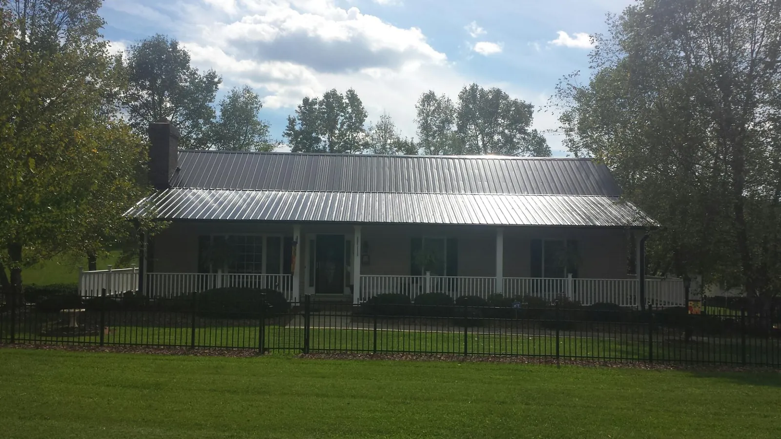 Gray metal roof on a brick ranch with a full width front porch — Gutter Guard Installation work by our crew in Lugoff