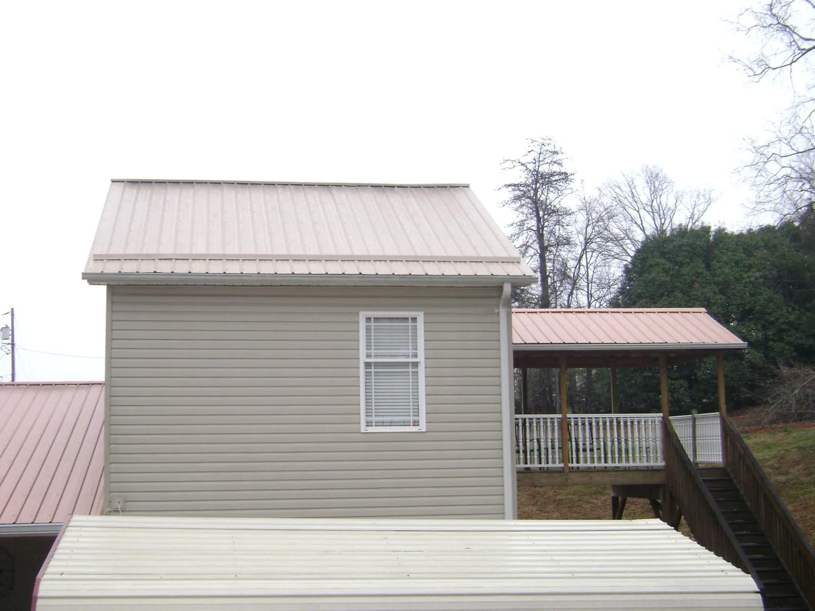 Tan metal roofs on a two story addition and attached porch, from a Roof Replacement job in Lugoff